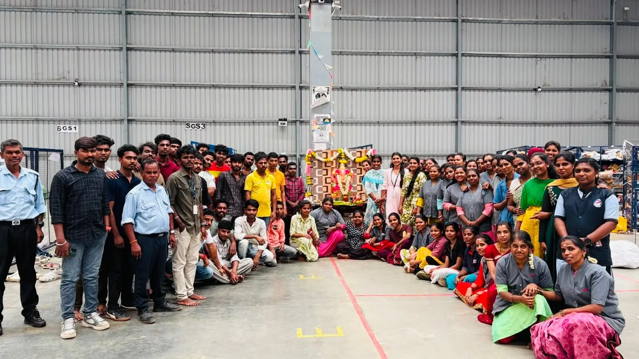 Warehouse teams gathered around a decorated shrine for the Ayudha Puja celebration